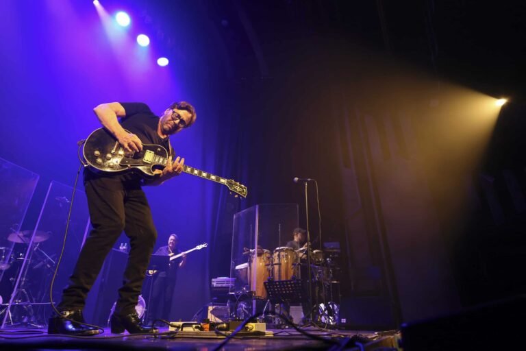 Qué significa la canción "Oye Cómo Va" de Carlos Santana 1 guitarrista tocando en un vibrante escenario